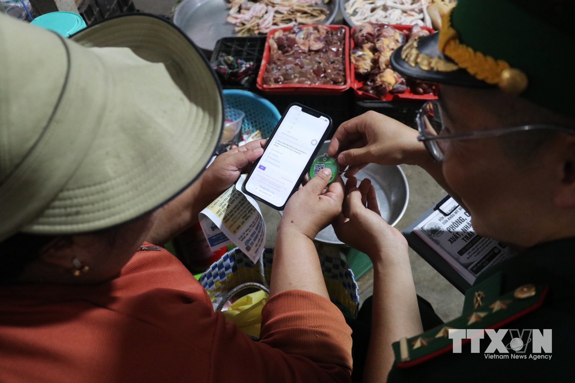 Đại úy Phạm Việt Tiến hướng dẫn người dân quét mã QR, sử dụng “Hòm thư điện tử tiếp nhận tin báo tố giác tội phạm”, tạo thêm kênh để nhân dân trực tiếp tham gia giữ gìn an ninh, trật tự khu vực biên giới. (Ảnh: Bùi Giang/TTXVN)